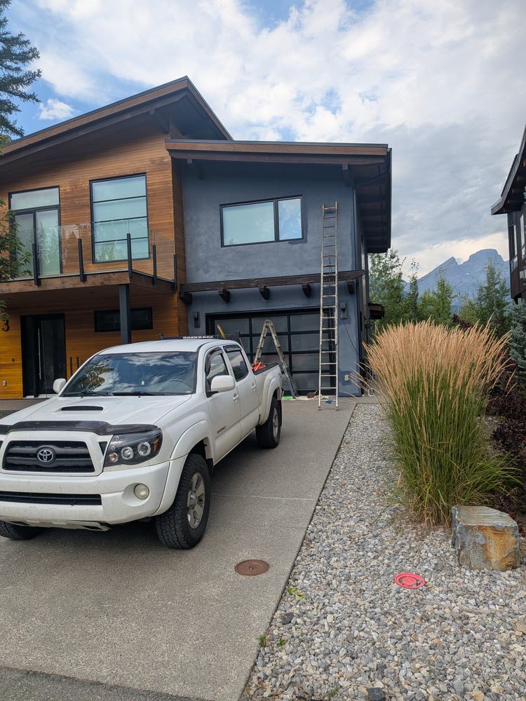 Modern two-storey home with wood and dark siding, ladder set up at the garage